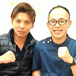 施術後に並んで座り、笑顔で拳を軽く構える二人の男性の写真。回復を実感した様子が伝わる。