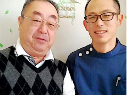 施術後に並んで座り、穏やかな表情でカメラを見ている二人の男性の写真。