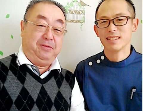 施術後に並んで座り、穏やかな表情でカメラを見ている二人の男性の写真。