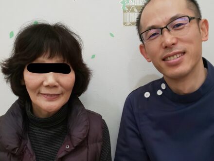 施術後に笑顔で並んで座る女性患者さんと施術者の様子。落ち着いた院内での記念写真